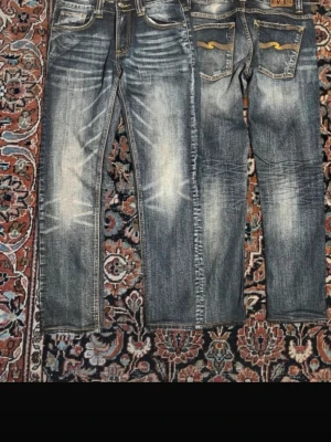 Nudie jeans - Jeans i storlek W30 L30 från Nudie. Blå denim med tvättad/washed look och snygga slitningar från användning. Modell thin finn.  Detaljer: 	•	Storlek: W30 	•	Midja: ca 40 cm 	•	Längd: ca 98 cm 	•	Benöppning: ca 17 cm 	•	Färg: Blå 	•	Skick: Bra använt skick (normalt slitage, inga hål) 