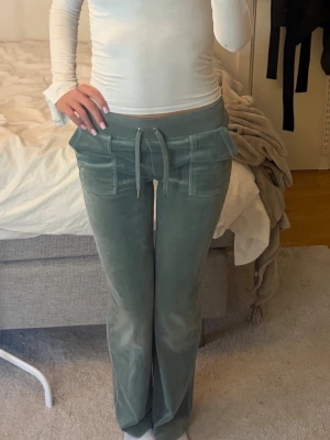 Gröna Juicy Couture mjukisbyxor - Säljer ett par gröna mjukisbyxor från Juicy Couture i storlek S. Byxorna har breda fickor framtill, dragsko i midjan och är gjorda i ett mjukt velourmaterial. Perfekta för en chill och avslappnad look. ‼️(Storlek S men sitter mer som en M)‼️