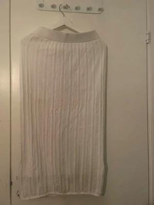 Vit stickad långkjol med struktur - Säljer en vit långkjol med stickad struktur och bred resår i midjan. Kjolen har ett diskret mönster med lodräta ränder och är perfekt för dig som gillar en enkel men ändå detaljrik stil.