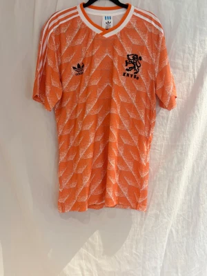 Nederländerna 1988  VAN BASTEN #12 - Säljer en klassisk Holland 1988 hemmatröja med Marco van Basten #12 på ryggen.  Riktig retro från året då Nederländerna tog sitt första stora guld, med Van Basten som en av turneringens absolut största spelare. Under den här tiden lirade han tillsammans med spelare som Ruud Gullit och Frank Rijkaard.  Clean och ikonisk tröja som passar perfekt för både samlare och vardag.   