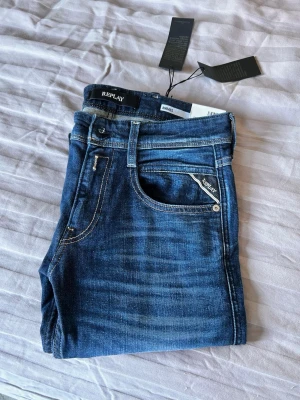 Mörkblå skinny jeans från Replay - Snygga mörkblå skinny jeans från Replay med klassisk femficksdesign och diskreta slitningar. Jeansen har en smal passform och är tillverkade i stretchigt denim för extra komfort. Perfekta för en trendig och avslappnad look. Nypris 1600