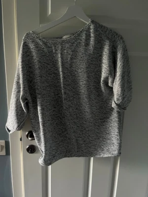 Gråmelerad oversized tröja - Säljer en gråmelerad  tröja med 3/4-ärmar och rund halsringning. Tröjan har en avslappnad passform och är tillverkad i ett mjukt, stickat material. Perfekt för lager-på-lager och chill dagar.