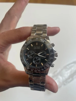 HUGO BOSS Watch  - Klockan är 22 cm lång (17 cm om man inte räknar med själva klockan). Den är enkel att göra mindre och större och jag kan även göra det själv för en liten extra slant (se sista bilden). Klockan är aldrig använd, helt ny! 🆕 Var inte rädd med att ge förslag och ge gärna bud! 🏆