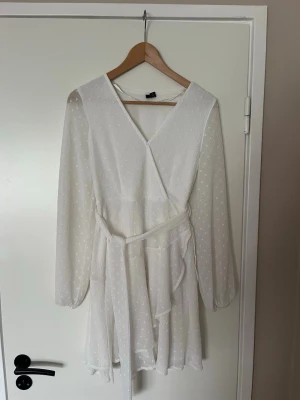 Vit klänning - Vit sommarklänning från Vero Moda. Genomskinligare armar och snöre runt midjan 