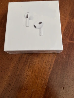 Apple AirPods 3rd generation - Trådlösa vita in-ear hörlurar från Apple, modell AirPods 3rd generation. Snygg och stilren design med rundade former och korta stjälkar. Levereras i originalförpackning och den stödjer MagSafe.
