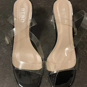 Genomskinliga klackar  - Klackar med genomskinliga remmar och klack. Svart fotplatta. Köpt på zalando för 262kr. Använda endast en gång, ser nya ut. Klackhöjd: 9,5 cm Strl: 37