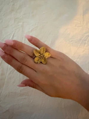 Guldig blomformad ring - Säljer en guld ring formaf som en blomma med detaljerade blad. Justerbar storlek!