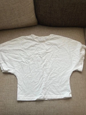 Vit oversized t-shirt med boxy fit - En vit oversized t-shirt med boxy passform och breda ärmar. T-shirten har rund halsringning och är tillverkad i ett mjukt bomullstyg. Perfekt för en avslappnad och trendig stil.. kan finnas nån mini fläck 