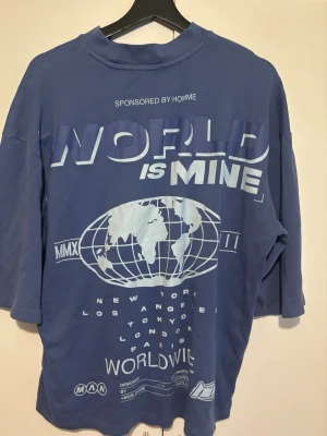 Blå oversized t-shirt  - Blå oversized t-shirt från . T-shirten har rund hals och trekvartsärm, samt en loose passform. Perfekt för en avslappnad streetwear-look.
