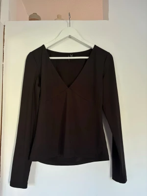 Svart v-ringad topp från Vero Moda - Snygg svart långärmad topp från Vero Moda med djup v-ringning. Enkel och stilren design i stretchigt material för bra passform. Passar både vardag och fest. Storlek M i mycket bra skick🤗