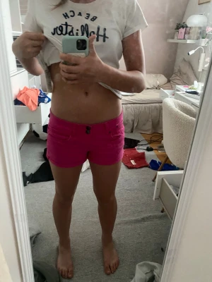 Rosa lågmidjade shorts  - Säljer ett par snygga rosa shorts från Hollister. De är lågmidjade med knapp och dragkedja framtill samt har fickor både fram och bak. Perfekta för varma dagar och ger en fräsch och färgstark look.