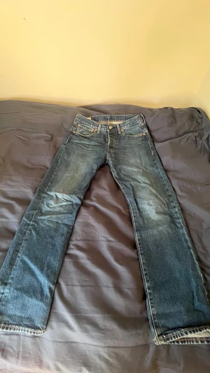 Levi's 501 - Klassiska blå jeans från Levi's med rak passform och fem fickor. Jeansen har en snygg tvättad look och detaljer som synliga sömmar och läderpatch bak i midjan. Perfekta för en avslappnad stil och funkar året runt.