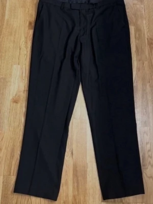 Svarta kostymbyxor från Dressmann - Storlek 38/30 - Snygga svarta kostymbyxor i klassisk design som passar lika bra till kontoret som till mer formella tillfällen. Enkla att matcha med kavaj eller skjorta! Varumärke: Dressmann. Storlek: 38/30. Regular fit. Material: 80% Polyester och 20% Viskos. Knäpps med knapp och dragkedja. Två djupa fickor framtill och två bakfickor. Säljs i mycket bra skick! Kika gärna in på mina andra annonser, jag säljer flera klädesplagg - såsom en matchande kavaj! Hör av dig vid frågor eller intresse!