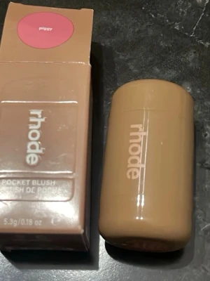 Rhode Pocket Blush Piggy - Rhode Pocket Blush i färgen Piggy är ett krämrouge i en smidig, beige förpackning. Färgen är en fräsch rosa nyans som ger kinderna ett naturligt glow. Perfekt att ha med i väskan för snabba touch-ups. Innehåller 5,3g.