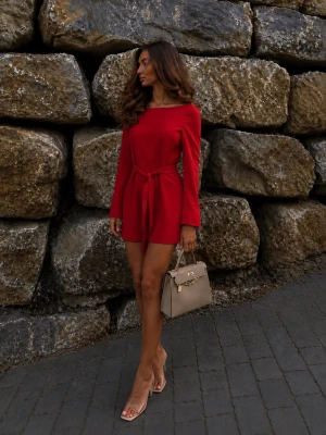 Röd långärmad jumpsuit med knytskärp - Trendig röd jumpsuit med långa ärmar och knytskärp i midjan. Modellen har en rak, något lös passform och korta ben. Snygg båturringning och stilren design utan synliga loggor. Perfekt för dig som vill sticka ut med färg. Materialet ser ut att vara mjukt och följsamt.