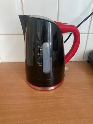 Svart och röd vattenkokare ICA - Elektrisk vattenkokare från ICA cook & eat i svart plast med rött handtag och botten. Rymmer upp till 1,7 liter och har tydlig nivåindikator på sidan. Snygg och praktisk design som passar i de flesta kök.
