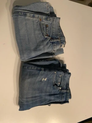 Blå raka jeans i klassisk modell - Två par blå jeans med klassisk femficksmodel. Ett par har en slitning vid fickan som jag köpte de med.