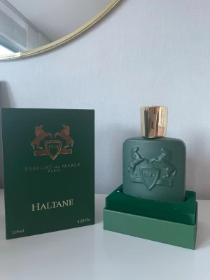 Parfums de Marly Haltane 125ml - Lyxig parfym från Parfums de Marly, modell Haltane. Flaskan är matt grön med guldfärgad kork och har en elegant relief med två hästar och sköld. Kommer i originalförpackning. Volym: 125 ml.