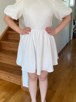 Miniklänning med puffärmar och öppenrygg - Vit - Studentklänning - En superfin vit klanning som passar dundret inför studenten! 🌸 Köpte den med förhoppning om att den skulle komma till användning men så blev det tyvärr inte. Helt ny, med etikett.🏷️ pris går självklart att diskutera! 