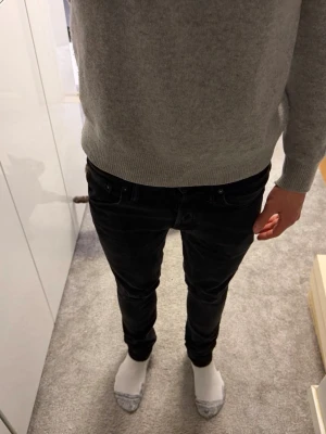 Svarta slim fit jeans från Jack & Jones - Svarta slim fit jeans från Jack & Jones med klassisk femficksdesign och normal midja. Jeansen har smal passform och är tillverkade i stretchigt denimtyg för extra komfort. Perfekta för en stilren och modern look.