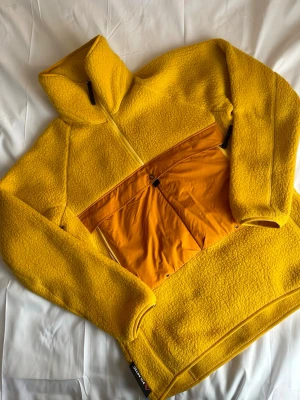 Gul fleecehoodie från Haglöfs - Authentic Haglöfs Polartec fleece jacket in bright yellow color.  * Warm teddy fleece material * Full zip * High neck * Clean condition * Super comfortable fit * Perfect gorpcore / outdoor style  Brand: Haglöfs Material: Polartec fleece Color: Yellow  Great for hiking, outdoor wear or everyday streetwear outfits. Feel free to message me for measurements or offers :)