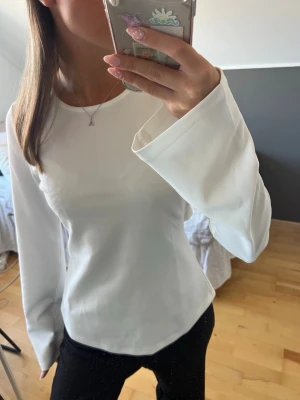 Vit långärmad topp från Ginatricot - Säljer en stilren vit långärmad topp från Ginatricot med supersnygg snörning i ryggen. Den är endast använd en gång😍🙌🏻