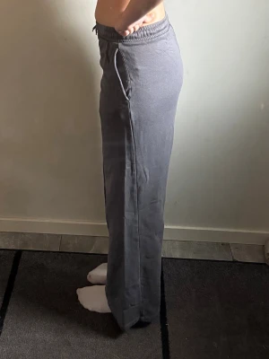 Grå mjukisbyxor med raka ben - Säljer ett par grå mjukisbyxor med raka ben och resår i midjan med snörning. Byxorna har sidofickor och är gjorda i ett mjukt och bekvämt material som passar perfekt för chill dagar. Enkel och stilren design som är lätt att matcha med olika toppar.