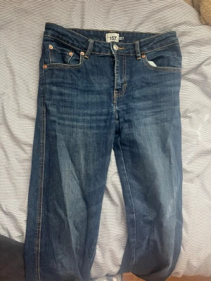 Mörkblå jeans från 157 - Snygga mörkblå jeans från 157 med klassisk femficksdesign och kontrastsömmar. Jeansen har raka ben och detaljerade bakfickor med knappstängning. Tillverkade i slitstark denim som ger en tidlös look.