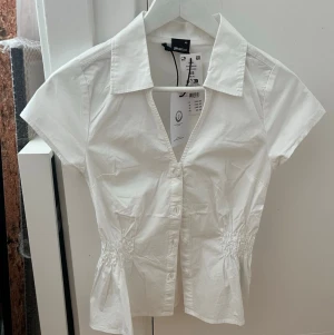 Smockad blus - Vit blus från gina med smockad midja. Endast provad, prislapparna kvar. Storlek XS. Bilder lånade från hemsidan