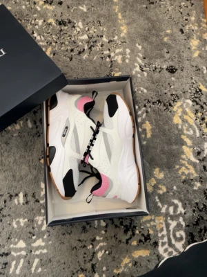 D****r sneakers med rosa mesh - Snygga sneakers från D***rmed vit och rosa mesh, svarta detaljer och reflexliknande ränder. Skorna har en chunky sula och cool design med blandade material som mesh och läder. Perfekt för dig som vill sticka ut med stilrena och trendiga sneakers.