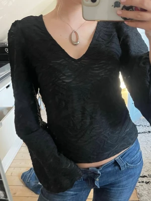 Svart blus med v-ringning från Vila - Supersnygg svart blus från Vila med v-ringad hals!  Toppen har långa, lätt puffade ärmar och lite strukturerat tyg. Perfekt som fest eller middags topp!