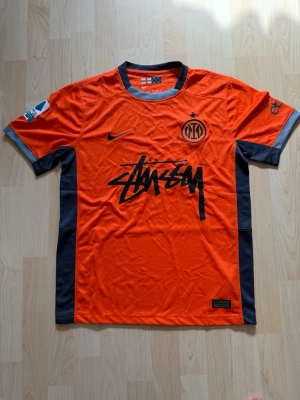 Inter x Stüssy Orange Kit Edition  - Stilren fotbollströja i helt nytt skick. Tröjan är inte använd en endaste sekund. Inter tröjan kombineras med det exklusiva streetwear märket Stüssy.