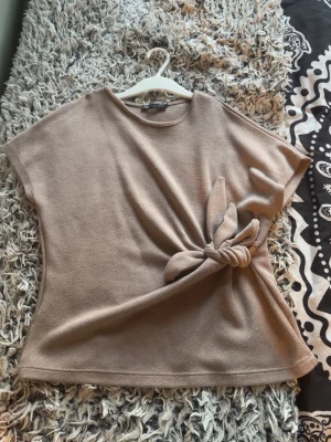 Beige stickad topp med knyt Zara  - Säljer en beige stickad topp från Zara med korta ärmar och snygg knytning i sidan. Knappt använd 💞
