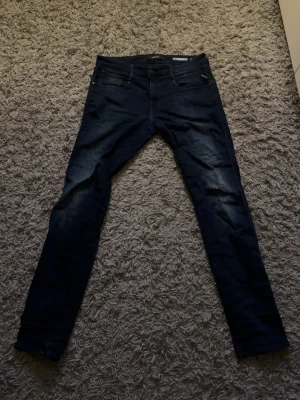 Mörkblå slim fit jeans från replay  - Snygga mörkblå slim fit jeans från replay  med klassisk femficksdesign och diskreta slitningar framtill. Jeansen har smal passform och är tillverkade i stretchigt denimtyg för extra komfort. Perfekta för en trendig och avslappnad look. Inga slitningar eller ngt sånt. Skriv iaf ni undrar ngt ✌️🙌W34 L34. 