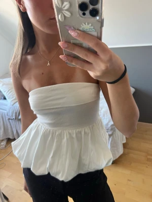 Vit bandeau topp - Säljer en vit bandeu topp med lite ”ballong-look”. Såå himla snygg!! Den har liten bit gummi på insidan framtill så toppen håller sig uppe. Endast använd ett fåtal gånger☺️🙌🏻