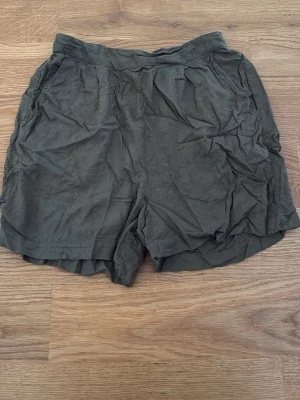 Olivgröna shorts från Pieces - Säljer ett par olivgröna shorts från Pieces i storlek XS. De har en avslappnad passform, elastisk midja och sidofickor. Perfekta för varma dagar och enkla att matcha med olika toppar.