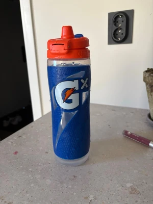 Blå Gatorade vattenflaska - Kostar 899 ny Säljer en blå vattenflaska från Gatorade med röd sportkork och vitt Gatorade-tryck. Flaskan är tillverkad i plast och har ett greppvänligt mönster samt praktiskt lock för enkel användning under träning eller sport.Kan användas med en podd alltså smak