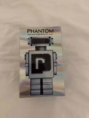 Phantom herrparfym från Paco Rabanne - Phantom är en herrparfym från Paco Rabanne med futuristisk robotdesign på flaskan. Förpackningen har en holografisk, silverfärgad yta och flaskan är formad som en robot med svart och silver detaljer. Perfekt för dig som gillar unika och moderna dofter.