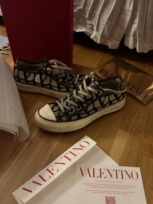 Valentino sneakers med grafiskt mönster - Snygga sneakers från Valentino med svart och vitt grafiskt mönster på canvasmaterial. Skorna har vita snören och en vit, robust gummisula. Perfekt för dig som vill sticka ut med ett exklusivt och trendigt val.