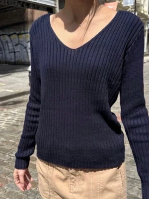 Mörkblå ribbstickad tröja - Snygg mörkblå ribbstickad tröja med v-ringning och långa ärmar. Tröjan har en smal passform och är perfekt för lager på lager. Materialet känns mjukt och följsamt, vilket gör den skön att bära hela dagen. Ifrån brandy