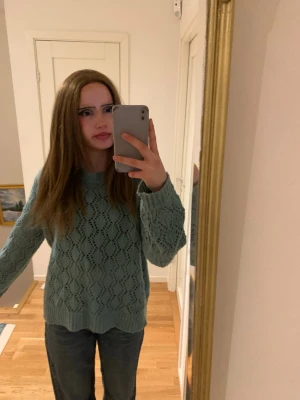 Blå stickad tröja med hålmönster - Mysig stickad tröja i ljusblå färg med snyggt hålmönster och rund hals. Tröjan har långa ärmar och ribbade muddar vid ärmslut och nederkant. Perfekt för att hålla sig varm och ändå se cool ut. Materialet känns mjukt och luftigt.