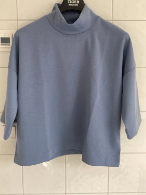 Blå polotopp från Carin Wester - Ny utan lappar. Säljer en stilren ljusblå polotopp från Carin Wester i storlek S. Toppen har en hög krage och trekvartsärmar, vilket ger en cool och avslappnad look. Materialet känns mjukt och är troligtvis polyester eller bomull. Perfekt att matcha med jeans eller kjol.