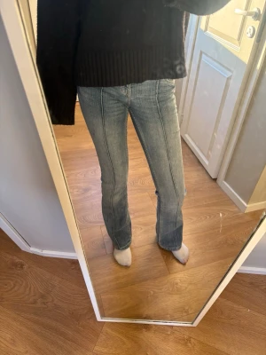 Blå bootcut jeans med sömdetaljer - Säljer ett par ljusblå bootcut jeans med markerade sömmar framtill och bakfickor. Jeansen har klassisk femficksdesign och är tillverkade i denim med lätt stretch. Perfekta för en avslappnad och trendig look.