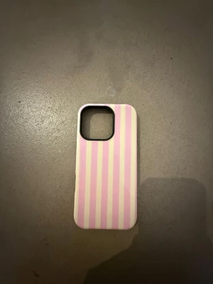 Rosa och gulrandigt mobilskal - Snyggt mobilskal med rosa och gula vertikala ränder. Skalets form är anpassad för en mobil med fyrkantig kameramodul. Materialet verkar vara plast och designen är enkel men trendig.