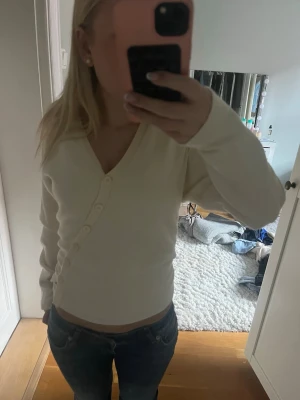 Korta med knappar - Snygg kofta med v-ringning och knäppning framtill. Långärmad modell i mjukt material som passar perfekt till jeans eller kjol. Enkel och stilren design som är lätt att matcha till olika outfits.