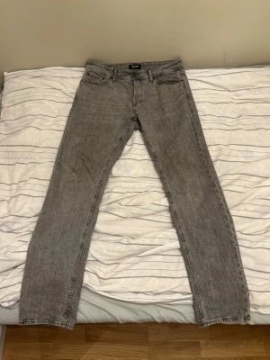 Grå Jeans Jack & Jones - Tapered Mike Jeans från Jack & Jones i storlek 31W 34L. Tapered passform betyder att jeansen är lite rymligare över lår/höfter för att sedan smalna av lite gradvis efter knäna och nedåt. Jag tyckte däremot dessa jeans var ganska så raka i passform men jag brukar ha 33W 32L i straight eller regular passform. 