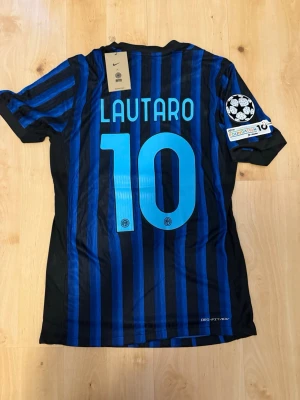 Lautaro #10 – Player Edition (storlek M) - Lautaro #10-tryck. Player Edition med Champions League patch på ärmen. Storlek M. Helt ny och aldrig använd. Säljs i befintligt skick. Skickas snabbt! 🚚💨  Mått för denna tröja (storlek M): (Uppmätta av leverantör – viss variation kan förekomma) • Halva bröstmåttet: 51 cm • Tröjans längd: 72,5 cm • Ärmbredd: 22,5 cm • Axelbredd: 43 cm • Ärmlängd: 39 cm • Manschettbredd: 18 cm  🔥 Player Edition-modell – tajtare passform än vanliga supportertröjor.