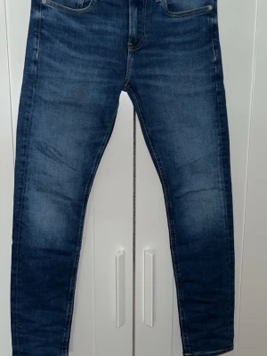 Blå slim fit jeans från Calvin Klein - Snygga blå slim fit jeans från Calvin Klein med klassisk femficksdesign och cK-logga på myntfickan. Jeansen har en lätt tvättad look och raka ben. Perfekta för dig som vill ha en stilren och modern jeansstil. Skriv om du har någon fråga🔥