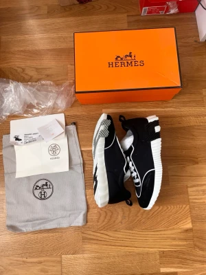 Svarta och vita sneakers  - Snygga svarta sneakers med vita detaljer och grovvit sula. Skorna har vita snören och kontrasterande vita linjer längs ovandelen. Klassisk låg modell med modern design och exklusiv känsla. Kommer med originalkartong och dustbag.