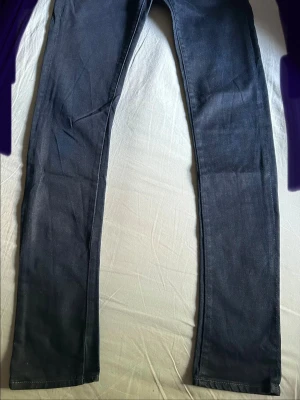 Mörkblå slim fit jeans från G-star raw - Snygga mörkblå slim fit jeans med klassisk femficksdesign och smala ben. Jeansen har en stilren look och passar perfekt till en avslappnad streetstyle. Innerbensmått är 82 cm. Bild på resten av måtten. 